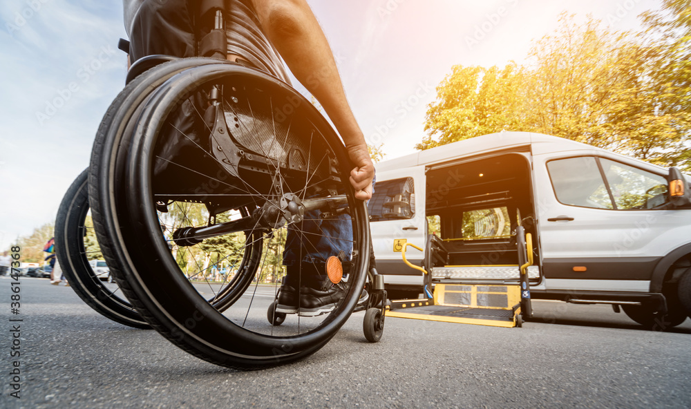 A man in a wheelchair moves to the lift of a wheelchair-accessible van.